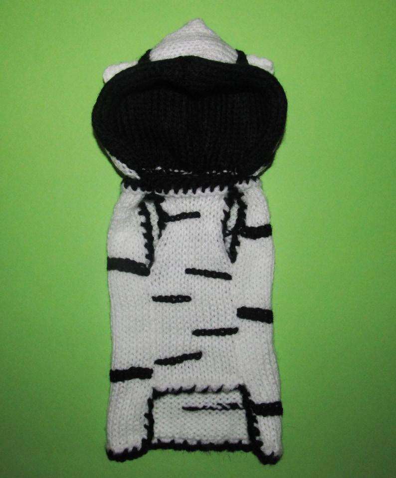 Peut inclure: Pull-over &agrave; capuche en tricot blanc et noir pour un petit chien ou un chat. Le pull a un motif ray&eacute; et une capuche noire.