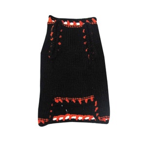 May include: Black knitted dog sweater with orange and white trim.