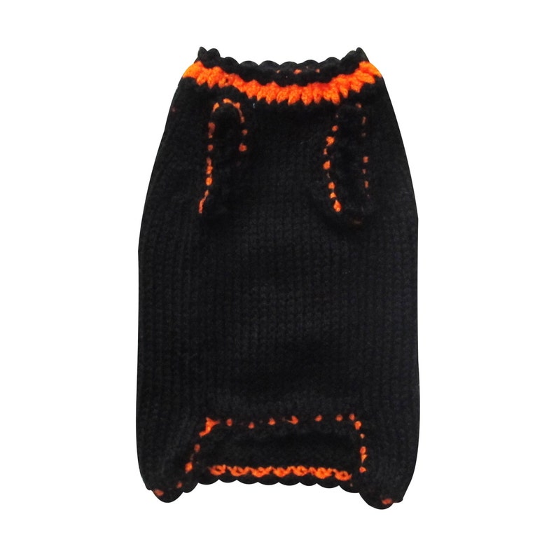 May include: Black knitted dog sweater with orange trim around the neck and armholes.