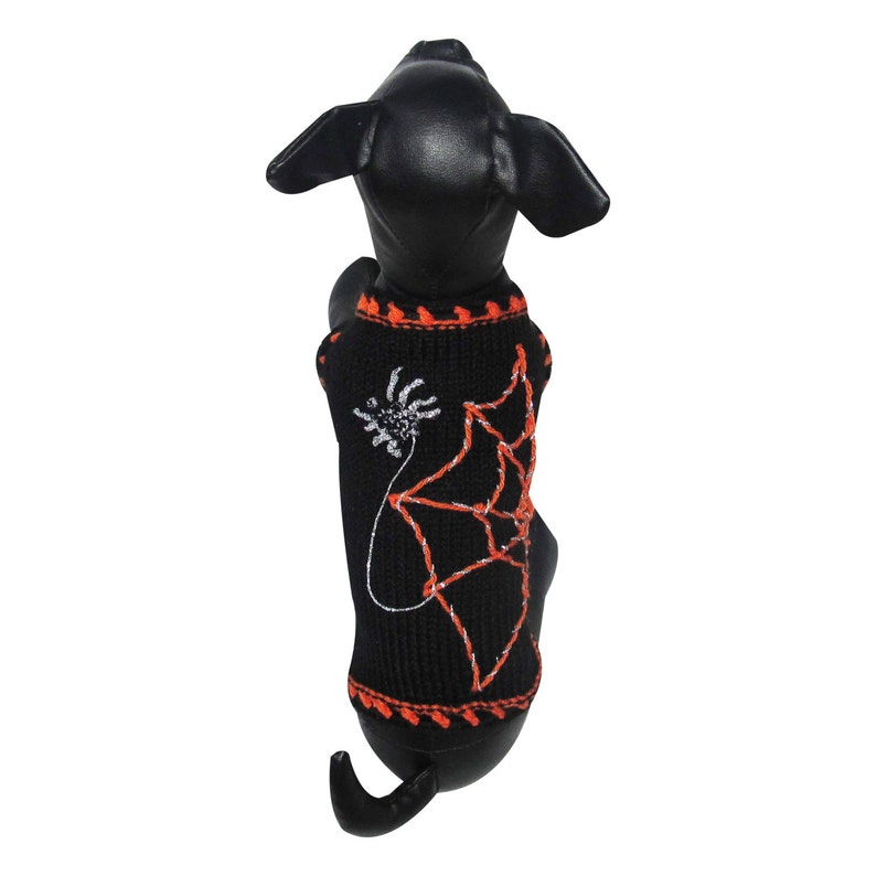 May include: Black dog sweater with an orange and silver spiderweb design.
