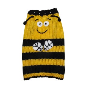 May include: A knitted sweater featuring a yellow and black horizontal striped pattern. The garment includes a cartoon bee face with white eyes, black eyebrows, and a smile, along with two small white wings attached to the center of the chest area.