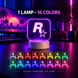 Puede incluir: Una lámpara LED cuadrada con el logotipo R-star de Rockstar Games. El texto 1 LAMP 16 COLORS aparece arriba. La lámpara se muestra en varios colores, incluidos rojo, azul, verde y morado, demostrando sus capacidades de cambio de color.