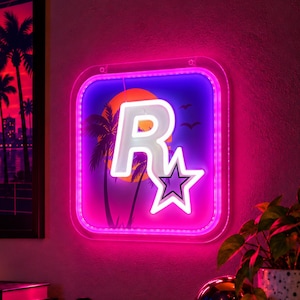 Op de afbeelding: Een vierkant LED-neonbord met een witte letter R en een sterlogo tegen een paarse en oranje zonsondergangachtergrond met silhouetten van palmbomen. Het bord is omlijst door een heldere, roze oplichtende rand.