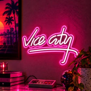 May include: A bright pink neon sign displaying the text Vice City in a cursive script font. The sign is mounted on a wall, emitting a vibrant glow that illuminates the surrounding area with a distinct pink light.