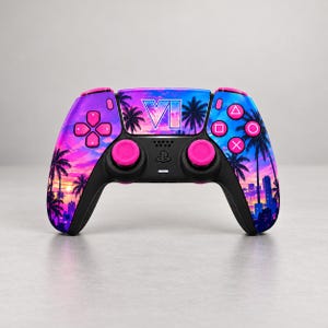 Op de afbeelding: Een draadloze videogamecontroller met een levendige zonsondergangafbeelding met palmbomen, stadssilhouetten en de tekst VI. Het apparaat heeft felroze analoge sticks, een richtingspad en actieknoppen op een zwarte basis.