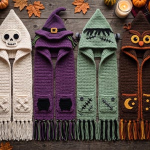 Könnte beinhalten: Vier gehäkelte Kapuzenschals. Der erste ist weiß mit Totenkopf-Kapuze und Knochen-Taschen. Der zweite ist lila mit Hexenhut-Kapuze und Kessel-Taschen. Der dritte ist hellgrün mit Monster-Kapuze und Naht-Taschen. Der vierte ist braun mit Eulen-Kapuze und Mond-Taschen. Alle Schals haben lange Fransen an den Enden.