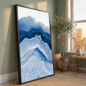Puede incluir: Una pieza de arte mural enmarcada, rectangular y vertical, con un patrón abstracto de piedra ágata en tonos azul marino, azul real y blanco. El diseño muestra texturas cristalinas concéntricas, onduladas y en capas dentro de un marco negro.