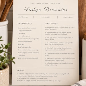 May include: A cream-colored recipe card titled The Family Recipe Collection Fudge Brownies. It lists ingredients like butter, sugar, eggs, cocoa powder, flour, and chocolate chips, with directions for baking in an 8-inch square pan.