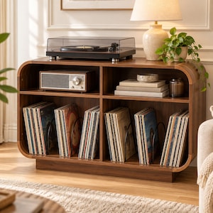 May include: A dark wood media console with rounded edges featuring four open storage compartments. The top surface holds a black turntable, a vintage-style radio, a stack of books, and a potted plant. The lower shelves are filled with vinyl records.
