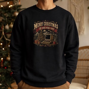 May include: A black crewneck sweatshirt featuring a graphic print of a vintage computer, a decorated Christmas tree, and gifts. The text reads Merry Christmas and git push origin main in a decorative banner above the computer illustration.