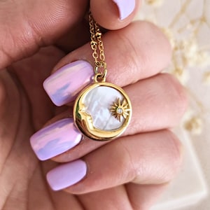 Op de afbeelding: Een gouden ketting met een halve maan hanger met een witte parelmoer inleg en een kleine glinsterende ster.