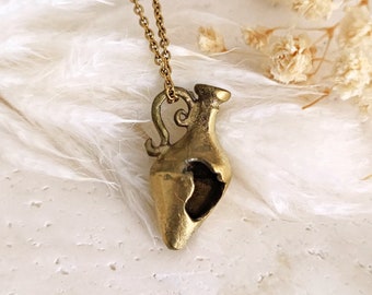 May include: A gold necklace with a broken amphora pendant. The amphora is a traditional Greek pottery vessel.