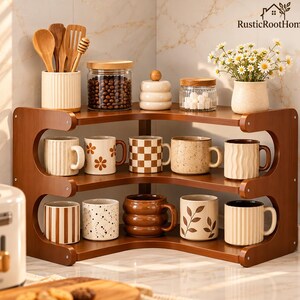 May include: A three-tiered wooden corner shelf holding ten ceramic mugs with various patterns, including stripes, checkers, flowers, and leaves. The top shelf displays a utensil holder, two glass jars, and a vase with white flowers.