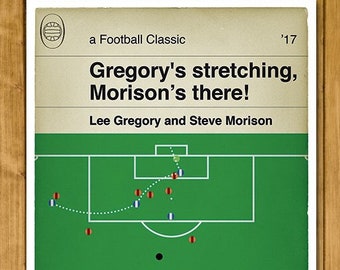 May include: A green and white illustration of a football field with players in red and blue uniforms. The text 'Gregory's stretching, Morison's there!' is at the top of the image. The text 'Lee Gregory and Steve Morison' is below the field.