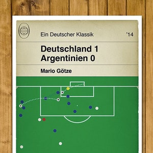 May include: A green and white soccer field with a blue and white soccer ball in the center. The text "Deutschland 1 Argentinien 0" is at the top of the image. The text "Mario Götze" is below the score. The text "Ein Deutscher Klassik '14" is at the top of the image.