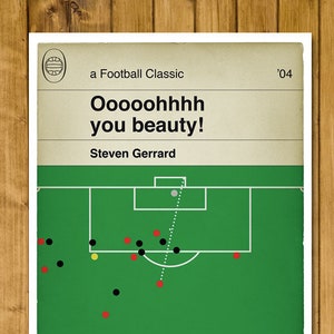 May include: A green soccer field with a white soccer ball in the goal. The text 'Oooooohhhh you beauty!' and 'Steven Gerrard' is on the poster. The poster also has the text 'a Football Classic' and '04'.