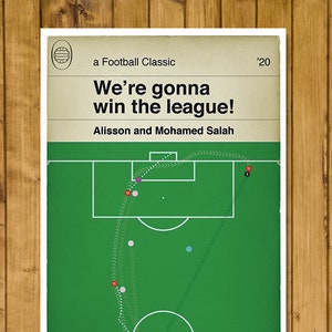 以下が含まれることがあります： 中央に白い円がある緑と白のサッカー場。画像の上部に「We're gonna win the league!」というテキストがあります。画像の上部に「a Football Classic '20」というテキストがあります。タイトルの下に「Alisson and Mohamed Salah」というテキストがあります。