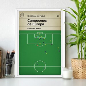 Puede incluir: Una impresión enmarcada en blanco con un campo de fútbol verde y un diseño de portada de libro vintage. El título dice "Campeones de Europa" con el subtítulo "Un Clasico de Futbol" y el autor "Fridolina Rolfö". El número "23" está impreso en la esquina superior derecha.
