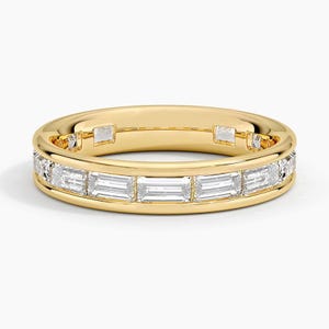 May include: A yellow gold band ring featuring a channel setting with a continuous row of clear, rectangular baguette-cut gemstones. The polished metal frame surrounds the stones, creating a sleek, uniform design around the entire circumference.