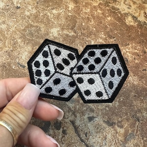 May include: Two black and white dice embroidered patches. The dice are sewn together and have a white background with black dots.