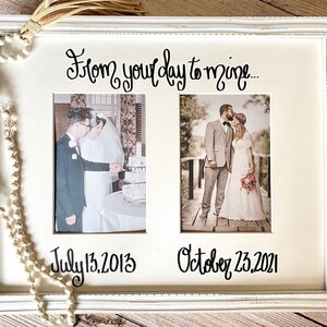 May include: A white framed photo display with two wedding photos. The top text reads "From your day to mine..." with the dates "July 13, 2013" and "October 23, 2021" below the photos. A decorative tassel and beaded garland are in the image.