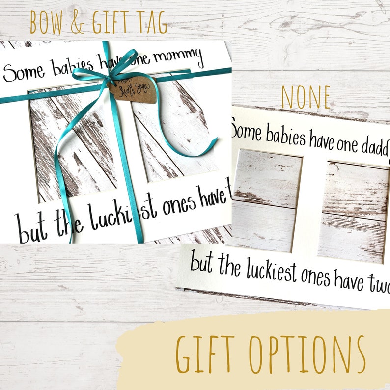 May include: White framed artwork with the text "Some babies have one mommy but the luckiest ones have..." and "Some babies have one daddy but the luckiest ones have two". A teal ribbon and gift tag are attached.