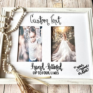 May include: White double photo frame with custom text and hand-lettered details. The frame holds two photos, with space for up to four lines of text. A beaded necklace with a tassel hangs on the left side.