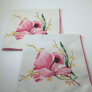 Peut inclure: Deux torchons en lin blanc avec des motifs floraux roses et jaunes et une bordure rouge.