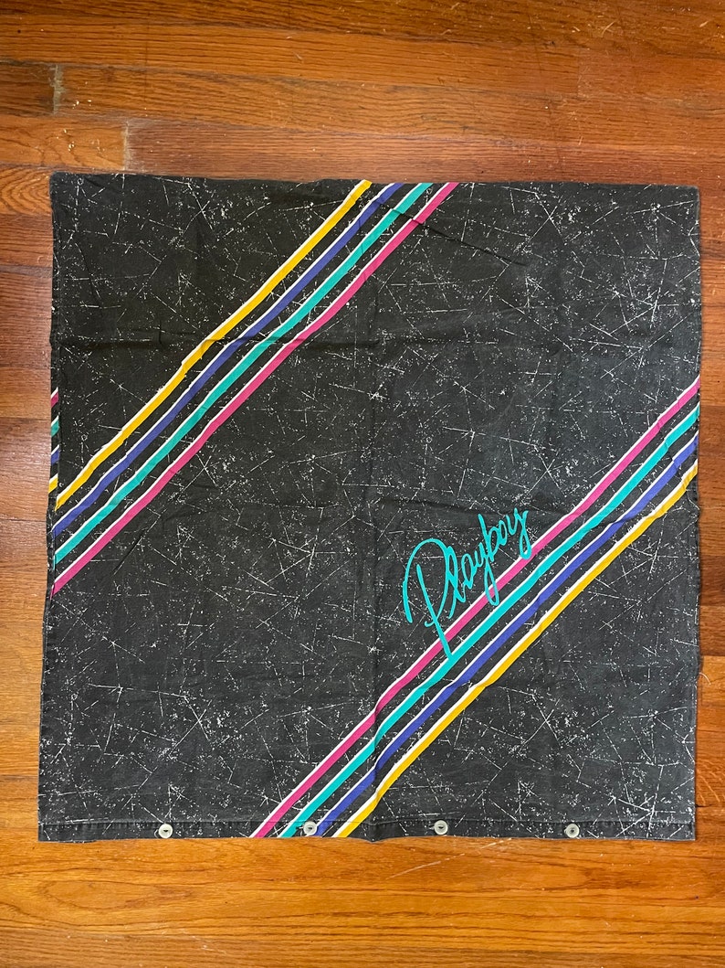 Peut inclure: Rideau de douche en tissu noir avec un motif de rayures color&eacute;es en diagonale et le mot "Playboy" en &eacute;criture turquoise.