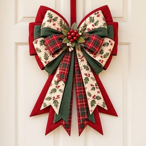 May include: A decorative fabric bow featuring layers of red, dark green, and cream-colored fabric with holly leaf and berry patterns, along with red and green plaid accents. A cluster of artificial red berries and green leaves sits at the center.