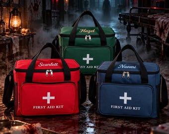 Puede incluir: Tres bolsas de primeros auxilios rectangulares en rojo, verde y azul. Cada bolsa presenta un símbolo de cruz blanca, el texto FIRST AID KIT y un nombre bordado en la solapa superior: Scarlett, Hazel y Naomi respectivamente.