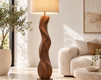 Könnte beinhalten: Eine Stehlampe mit einem hohen, skulpturalen Fuß aus dunkelbraunem Holz in einer fließenden, organischen, gedrehten Form. Die Lampe ist mit einem zylindrischen, hellbeigen Stoffschirm versehen, der ein warmes, sanftes Licht abgibt.