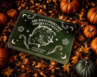 May include: A dark green Ouija board with a raven illustration, surrounded by orange pumpkins and autumn leaves. The board features the alphabet, numbers, and the words "GOOD BYE". A spooky, seasonal theme.