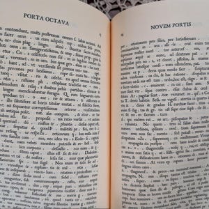 May include: Open book with two pages of Latin text. The left page is labeled "Porta Octava" and the right page is labeled "Novem Portis". The text is in black ink on aged, off-white paper. The book is open, revealing the text.