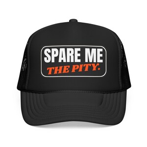 Pode incluir: Um boné trucker preto com um emblema retangular no painel frontal. O emblema tem uma borda branca e contém o texto SPARE ME em letras brancas em negrito, com as palavras THE PITY. impressas em laranja abaixo da primeira linha.