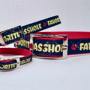 May include: Three dog collars with a blue background and yellow text that reads "Favorite Asshole". The collars are red on the back side.
