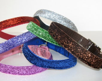 May include: A collection of colorful dog collars with glitter accents. The collars are in various colors, including red, silver, green, purple, blue, pink, and brown. Each collar has a shiny, glittery surface and a buckle closure.