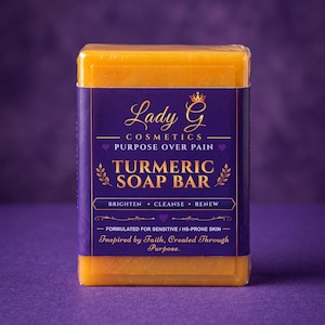 Puede incluir: Una pastilla de jabón de cúrcuma rectangular envuelta en plástico transparente con una etiqueta morada. La etiqueta presenta el texto Lady G Cosmetics, Purpose Over Pain, Turmeric Soap Bar, Brighten, Cleanse, Renew y Formulated for Sensitive / HS-Prone Skin.