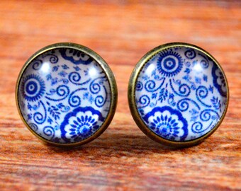 May include: A pair of blue and white patterned earrings with a bronze setting.