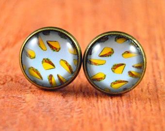 May include: A pair of round, bronze-colored earrings with a white background and a pattern of yellow tacos.