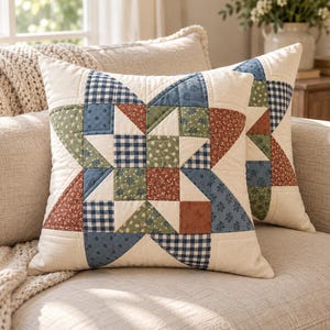May include: A square throw pillow featuring a patchwork star design in cream, navy blue, sage green, and terracotta. The pattern incorporates a mix of solid colors, small floral prints, and a navy blue gingham check, all finished with visible quilting stitches.