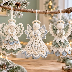 May include: Three crocheted angel ornaments hanging from a branch. Each angel features a cream-colored head with a halo, intricate lace-like wings, and a layered skirt in shades of cream, sage green, and dusty blue, accented with small beads.