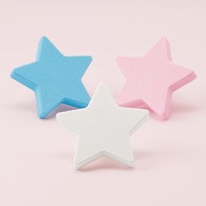 May include: Three star-shaped objects arranged in a cluster. One star is light blue, one is light pink, and one is white. Each star has a smooth, matte finish and a uniform five-pointed shape with clean, defined edges and a flat surface.