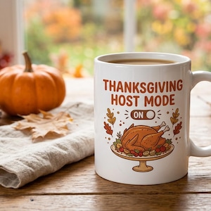 May include: A white ceramic mug featuring the text THANKSGIVING HOST MODE ON with a toggle switch graphic and an illustration of a roasted turkey on a platter surrounded by colorful autumn leaves in shades of orange, red, and brown.