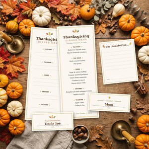 Puede incluir: Un juego de men&uacute;s de Acci&oacute;n de Gracias que incluye dos tarjetas de men&uacute; altas, una tarjeta de gratitud titulada I'm thankful for y dos tarjetas de lugar etiquetadas como Uncle Joe y Mom, impresas en papel crema con bordes dorados.
