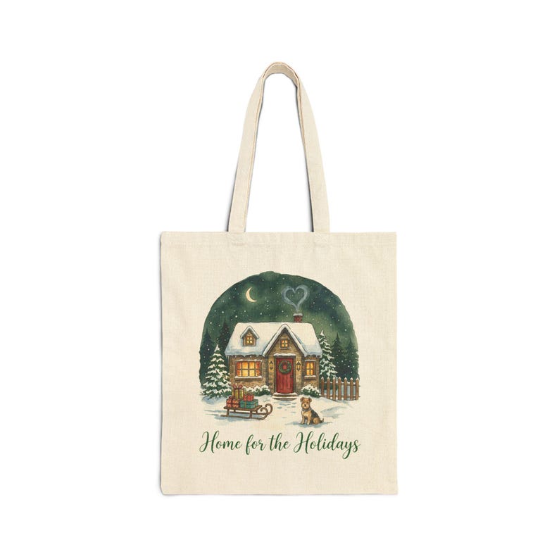 A natural beige canvas tote bag in the Natural color variant showing the snowy Christmas cottage "Home for the Holidays" print on a plain light-gray background.
