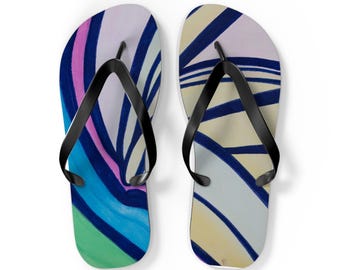 May include: A pair of flip-flops featuring black rubber thong straps and a colorful abstract pattern on the footbeds. The design includes sweeping lines in shades of navy blue, bright pink, light green, and pale yellow across the surface.