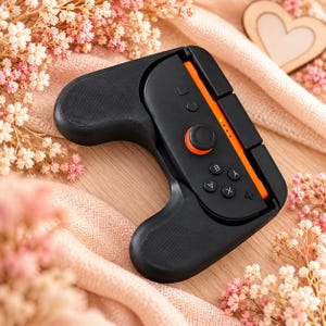 Peut inclure: Une poignée de manette de jeu noire avec un design texturé et une fente centrale contenant un module de manette noir avec un accent latéral orange, un joystick circulaire à base orange et quatre boutons marqués A, B, X et Y.