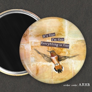 May include: A round magnet with a watercolor-style image of a hummingbird in flight against a yellow and orange background. The text "It's fine I'm fine Everything is fine" is printed on the magnet. The order code "ARHB" is printed on the bottom of the magnet.