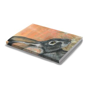 May include: A canvas print featuring a detailed illustration of a jackrabbit. The artwork showcases the rabbit's profile with a focus on its eye and long ears. The background has an orange and tan textured appearance.